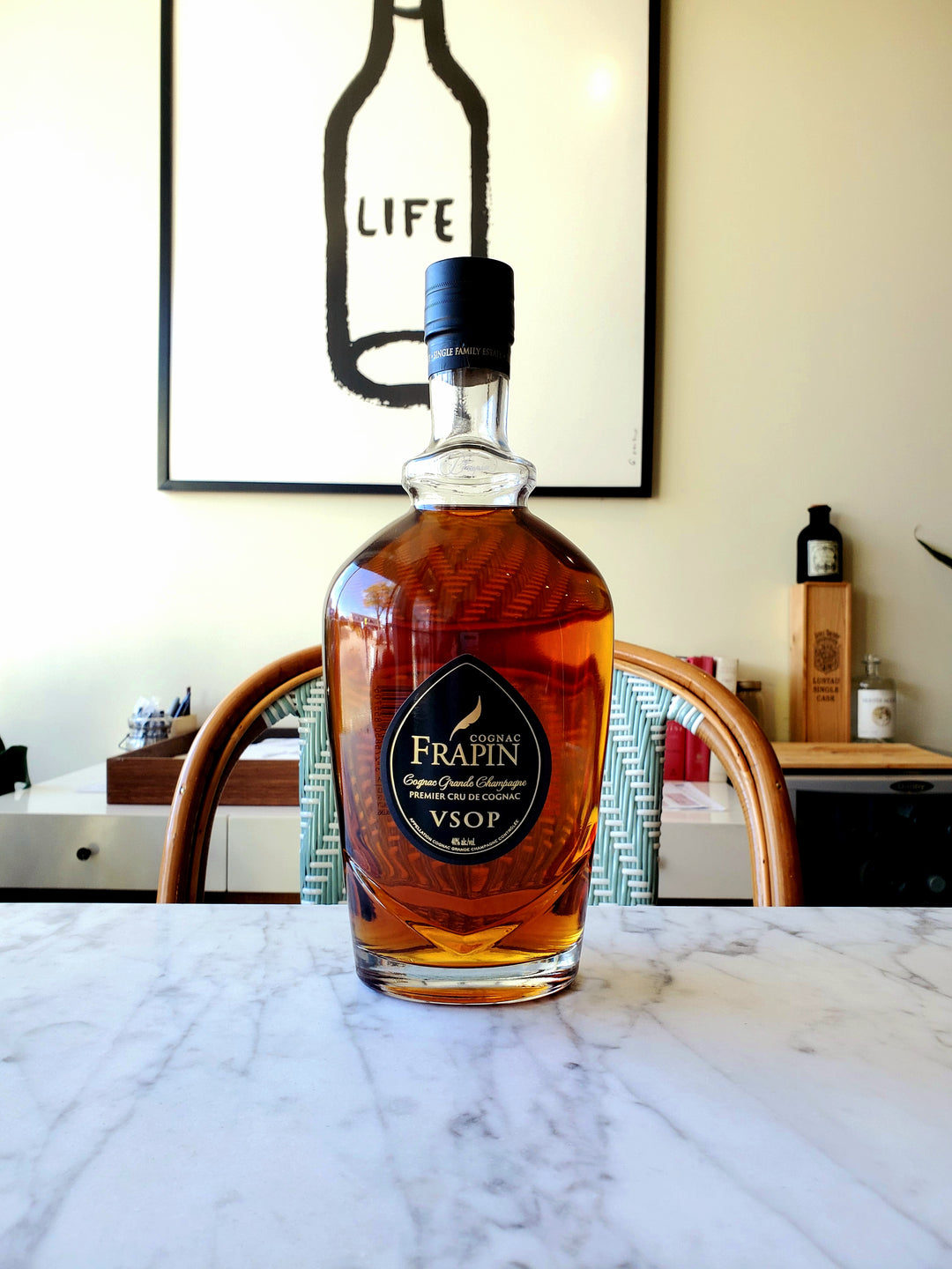 A bottle of Frapin VSOP Cognac placed on a marble surface with a artistic background.